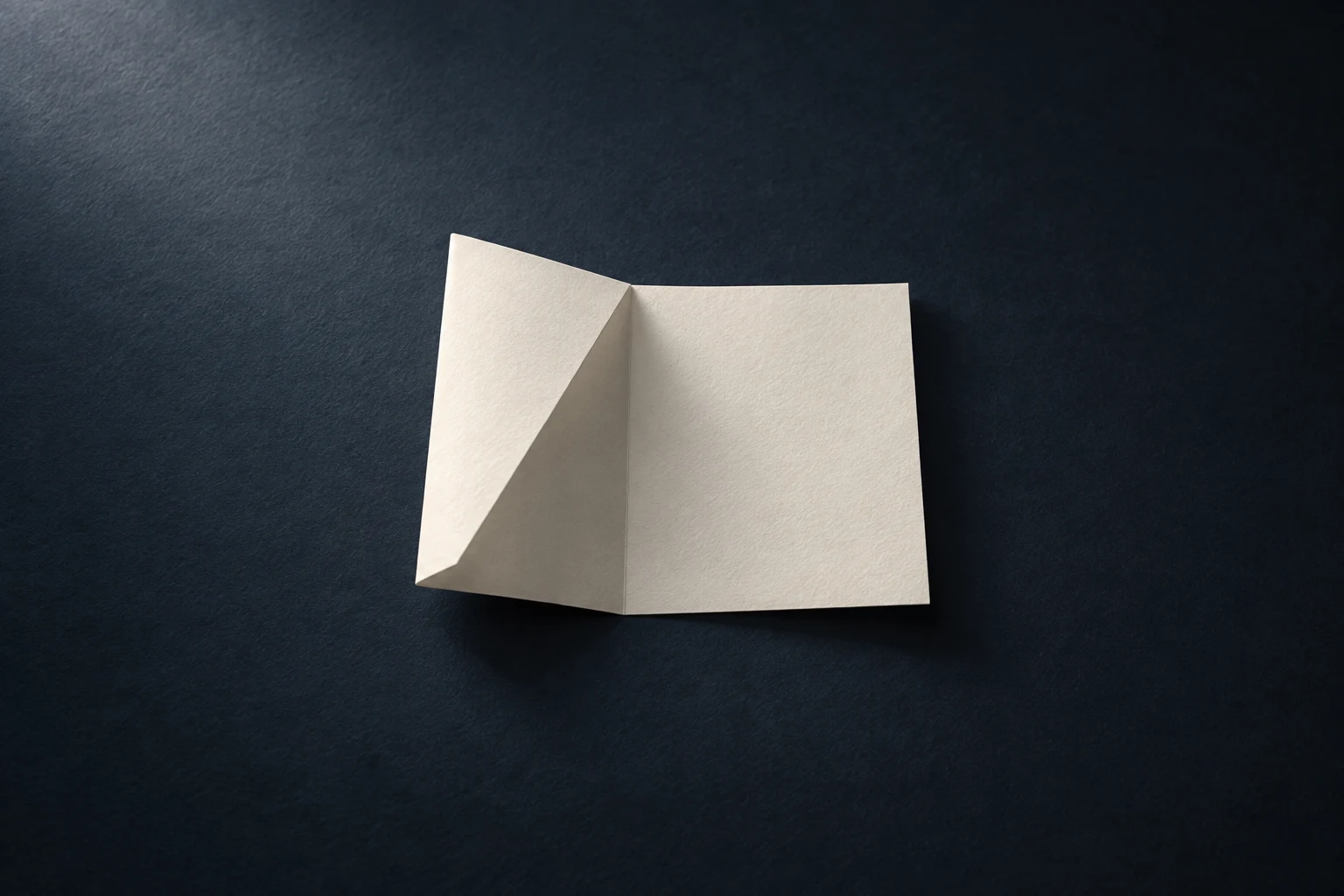 Une feuille blanche pliée deux fois sur une surface bleu nuit