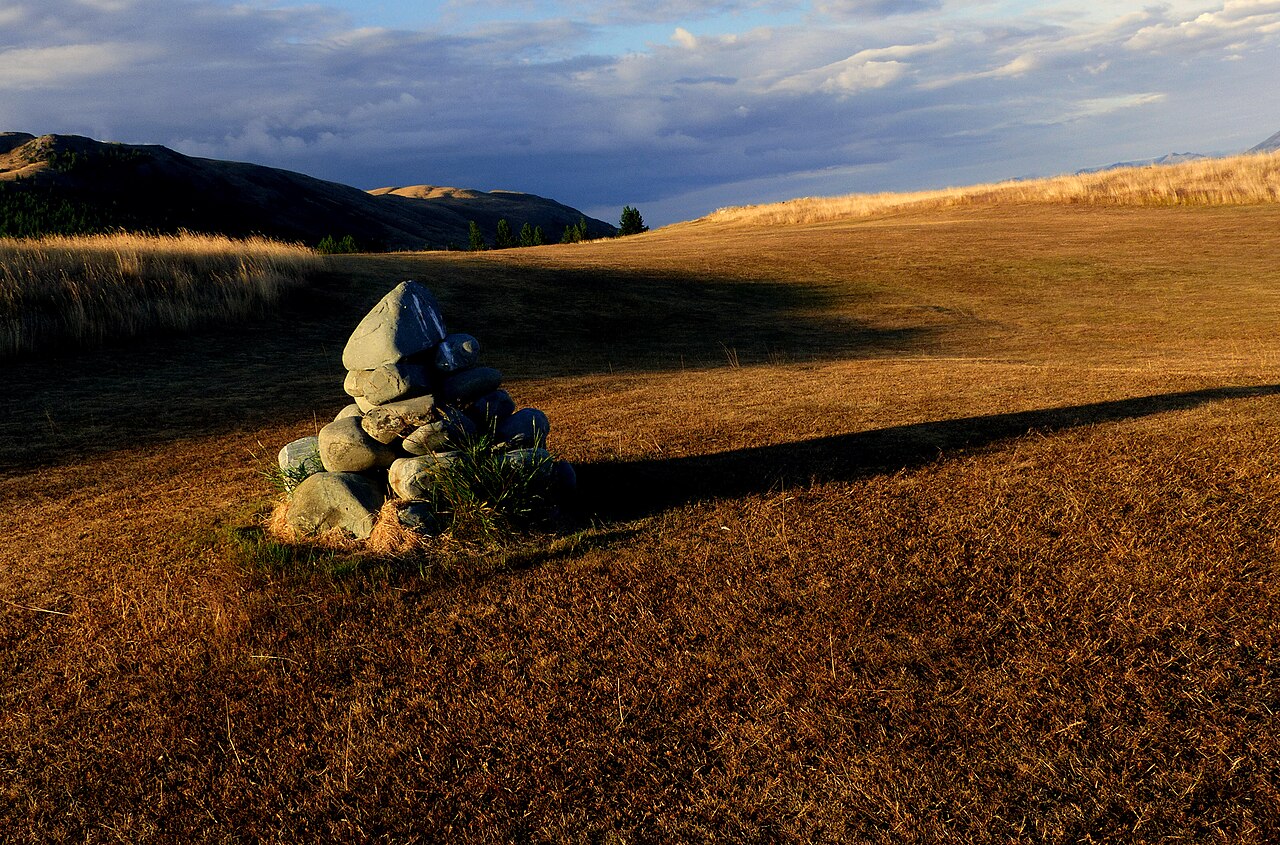 A tall cairn made from stones balanced in a tapered stack against a mountain landscape.